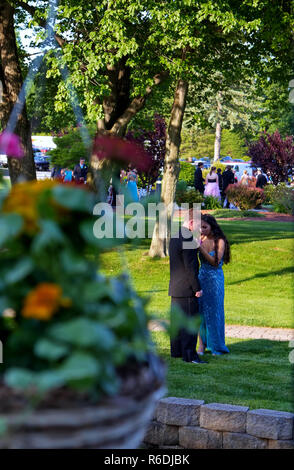 Plainville, CT USA. June 2013. Young woman is cautiously pinning her date`s boutonniere before the prom. Stock Photo